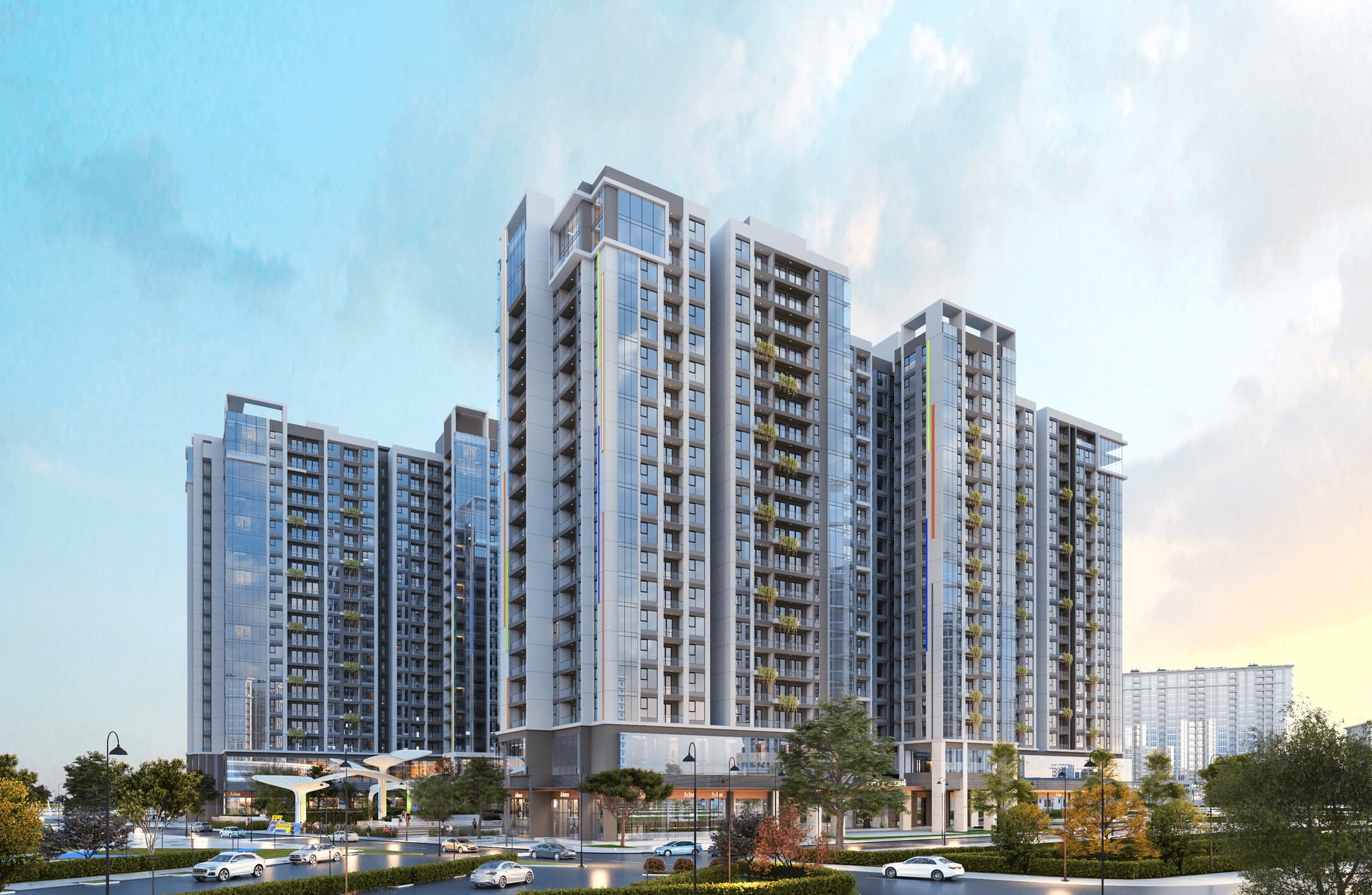 Modern high-rise residential buildings with landscaped areas and vehicles in the foreground under a blue sky.