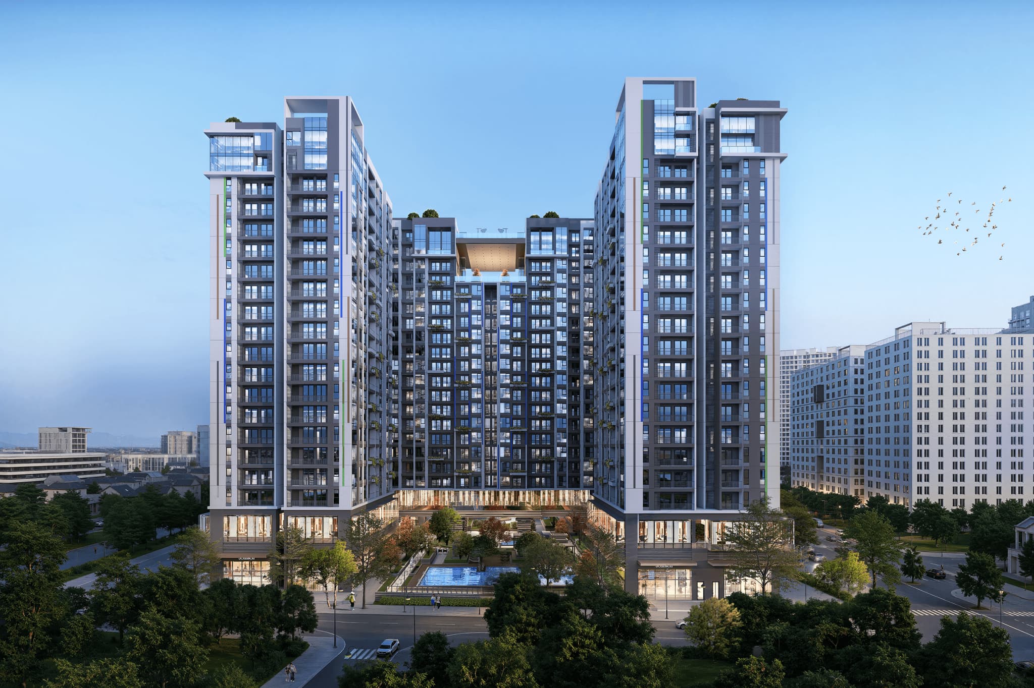 Modern residential building with multiple floors, large windows, and a central pool area, set against a clear blue sky.